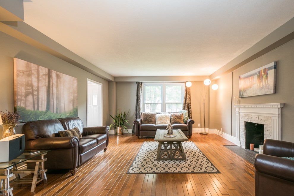 This is an example of a large industrial formal enclosed living room in Toronto with grey walls, medium hardwood floors, a standard fireplace, a stone fireplace surround and no tv.