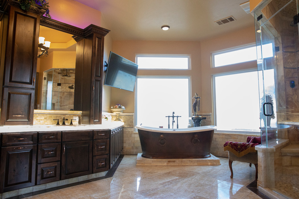 Inspiration for a large mediterranean master beige tile and travertine tile ceramic tile and beige floor freestanding bathtub remodel with raised-panel cabinets, dark wood cabinets, a two-piece toilet, beige walls, an undermount sink, quartzite countertops, a hinged shower door and white countertops