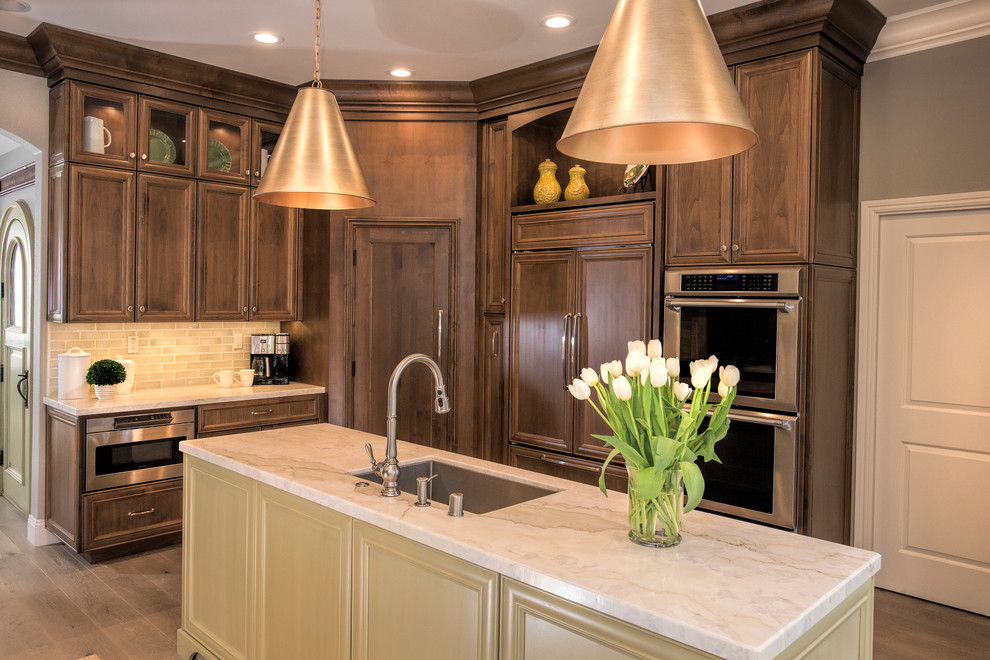 Kitchen - large transitional light wood floor kitchen idea in San Francisco with an undermount sink, recessed-panel cabinets, medium tone wood cabinets, quartzite countertops, green backsplash, glass tile backsplash, paneled appliances, two islands and multicolored countertops