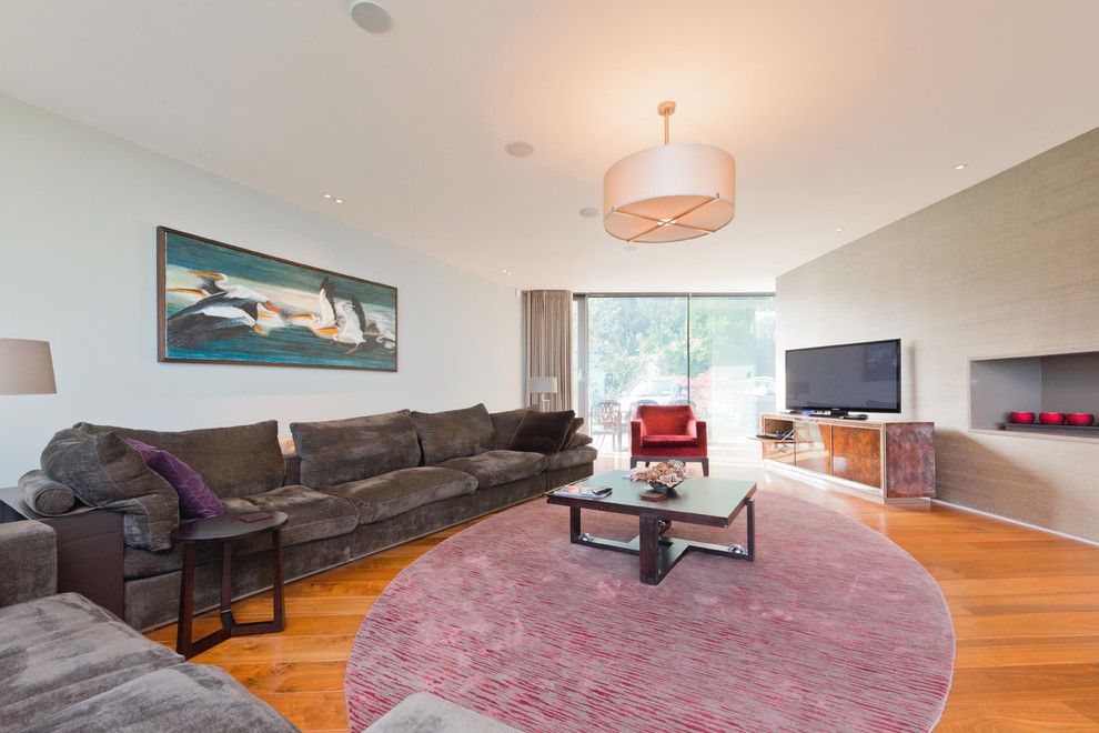 Photo of a large modern living room in Dublin with medium hardwood floors and a freestanding tv.