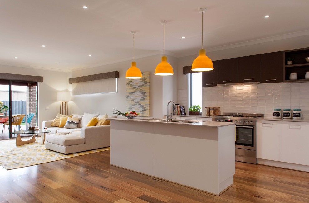 This is an example of a mid-sized contemporary single-wall eat-in kitchen in Melbourne with a double-bowl sink, flat-panel cabinets, granite benchtops, white splashback, ceramic splashback, stainless steel appliances, light hardwood floors and with island.