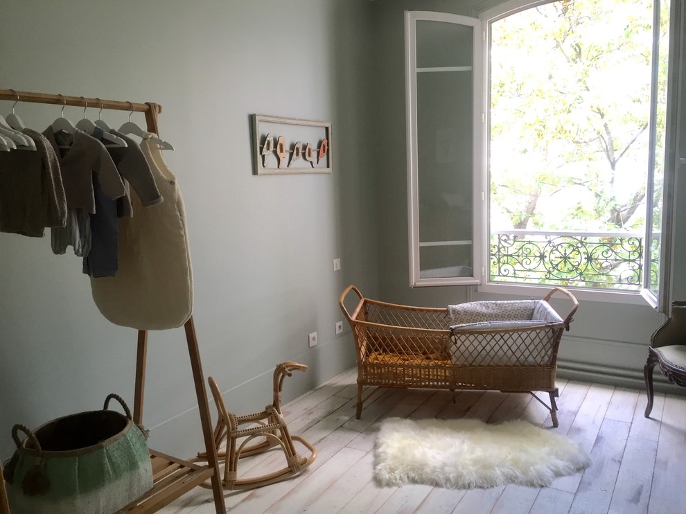 Design ideas for a mid-sized transitional gender-neutral nursery in Paris with green walls, light hardwood floors and beige floor.