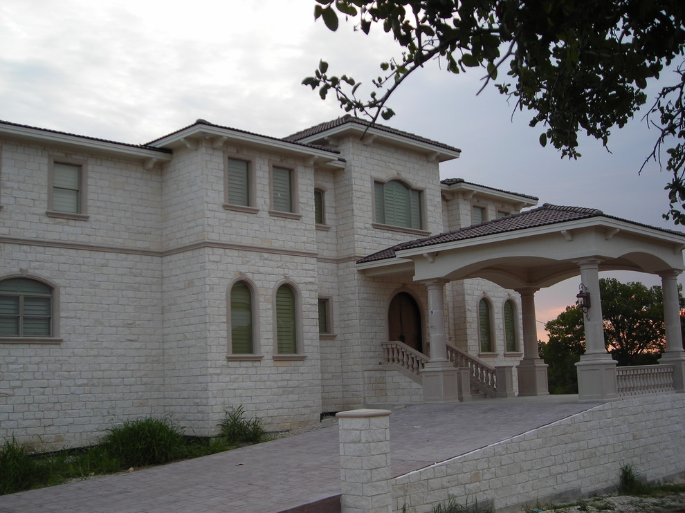 This is an example of an expansive mediterranean three-storey white exterior in Austin with stone veneer and a hip roof.