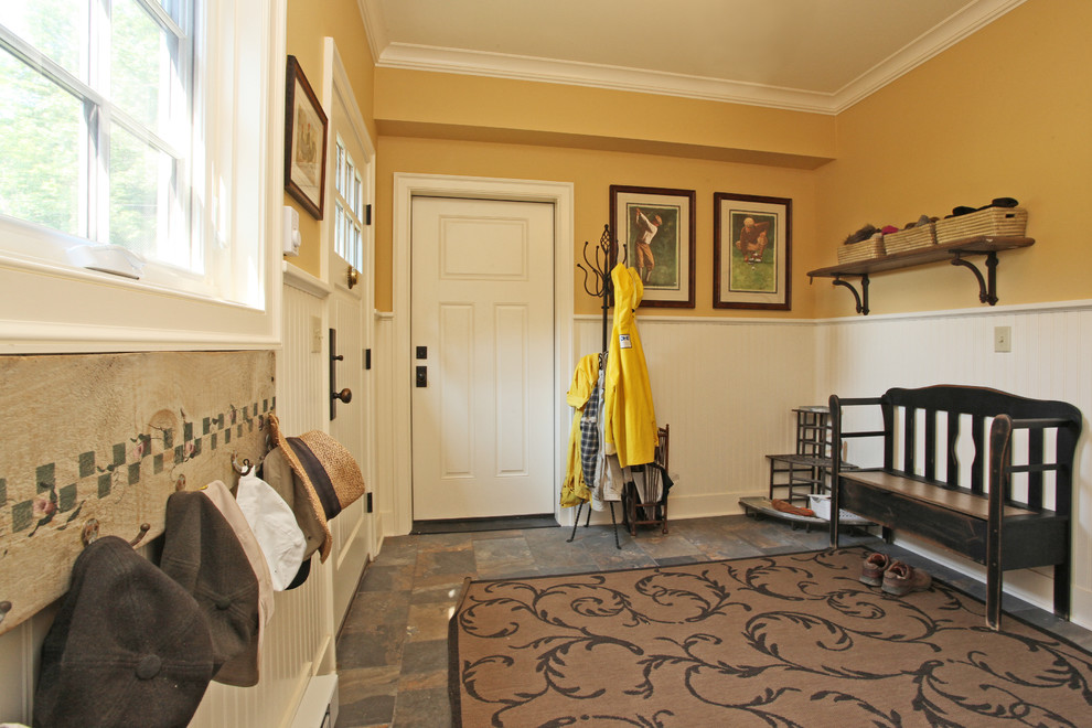 Photo of a country mudroom in New York with yellow walls, dark hardwood floors, a white front door and a pivot front door.