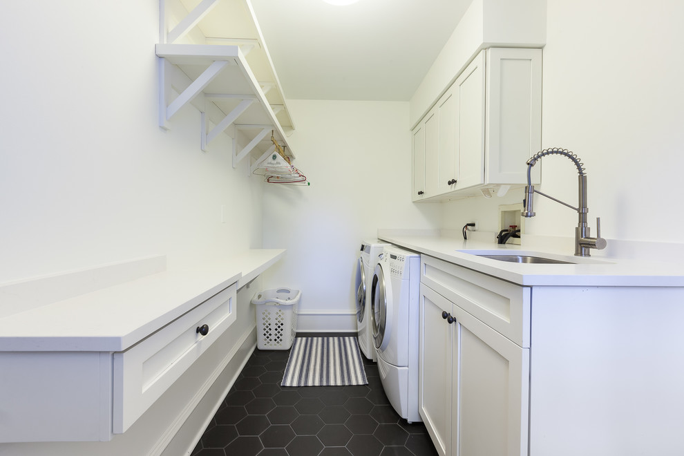 Design ideas for a large transitional utility room in Chicago with an undermount sink, shaker cabinets, white cabinets, quartz benchtops, white walls, ceramic floors, a side-by-side washer and dryer, black floor and white benchtop.