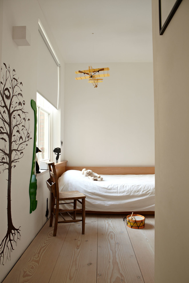 Photo of a scandinavian kids' room in London with white walls and light hardwood floors.