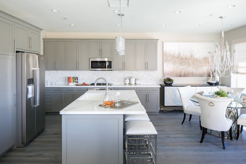 Example of a mid-sized transitional eat-in kitchen design in Orange County with an island, shaker cabinets, gray cabinets, white backsplash and stainless steel appliances