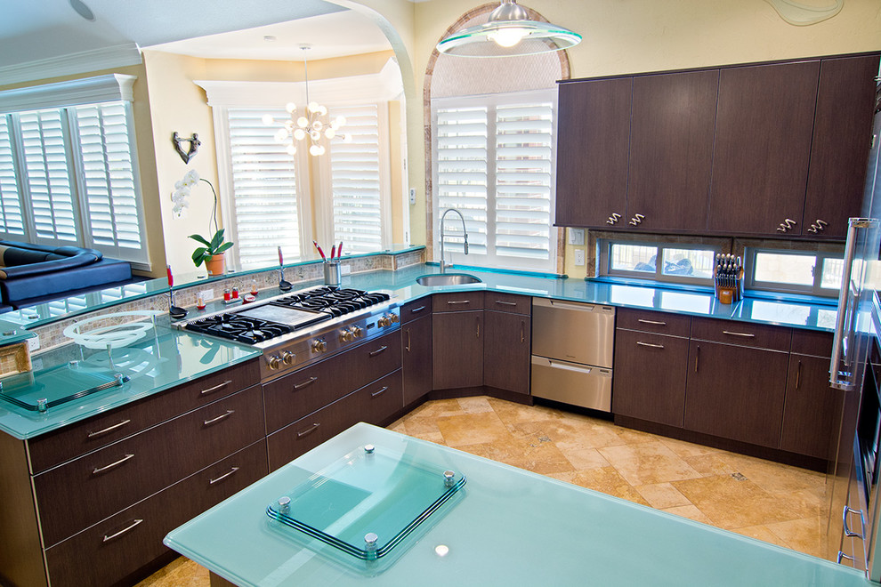 Photo of a large eclectic u-shaped eat-in kitchen in Dallas with an undermount sink, flat-panel cabinets, dark wood cabinets, glass benchtops, stainless steel appliances, travertine floors and turquoise benchtop.