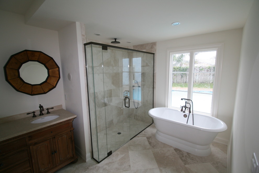 Photo of a large midcentury master bathroom in Miami with raised-panel cabinets, medium wood cabinets, a freestanding tub, an open shower, beige tile, stone slab, white walls, an undermount sink, quartzite benchtops, ceramic floors, beige floor and a hinged shower door.