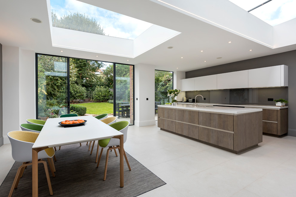 Inspiration for a contemporary eat-in kitchen in London with an undermount sink, flat-panel cabinets, white cabinets, black splashback, glass sheet splashback, with island and grey floor.