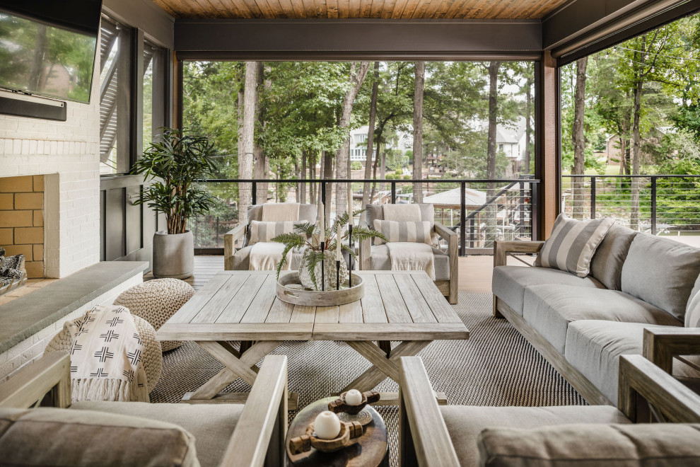 This is an example of a mid-sized beach style backyard and ground level deck in Charlotte with with fireplace, a roof extension and cable railing.