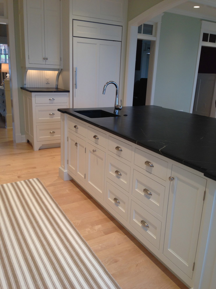Inspiration for a large traditional u-shaped eat-in kitchen in Portland Maine with an undermount sink, beaded inset cabinets, white cabinets, soapstone benchtops, white splashback, subway tile splashback, panelled appliances, light hardwood floors and with island.