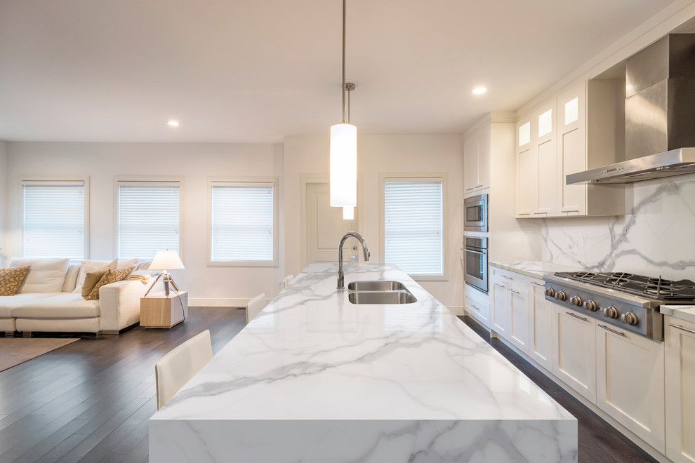 This is an example of a large transitional single-wall open plan kitchen in Madrid with recessed-panel cabinets, white cabinets, marble benchtops, white splashback and with island.