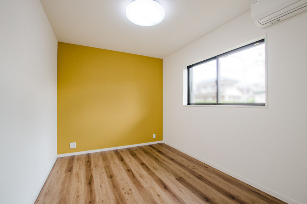 Nordisk inredning av ett pojkrum kombinerat med skrivbord och för 4-10-åringar, med gula väggar, mellanmörkt trägolv och brunt golv