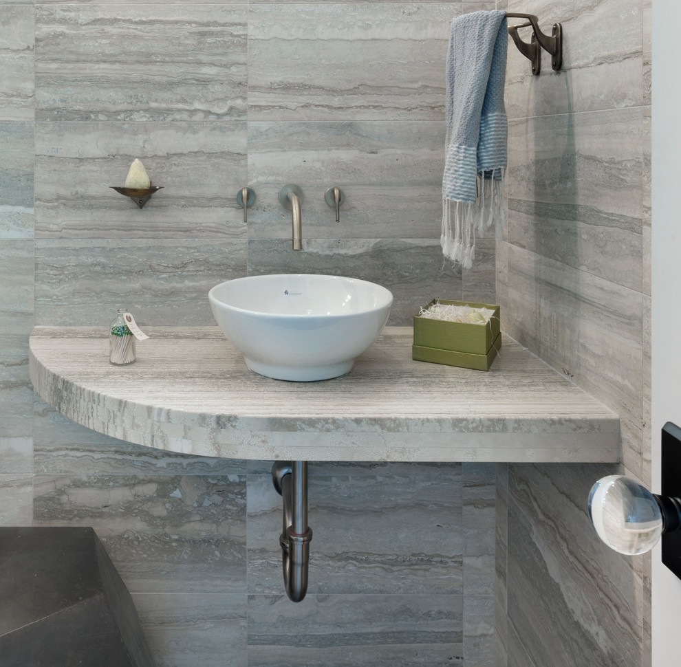 Small contemporary powder room in New York with a vessel sink, limestone benchtops, gray tile and limestone.