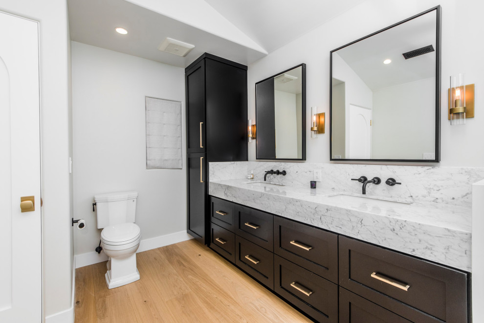 Large transitional master bathroom in Los Angeles with black cabinets, marble, white walls, light hardwood floors, an undermount sink, marble benchtops, beige floor, grey benchtops, a double vanity, a built-in vanity, vaulted and shaker cabinets.