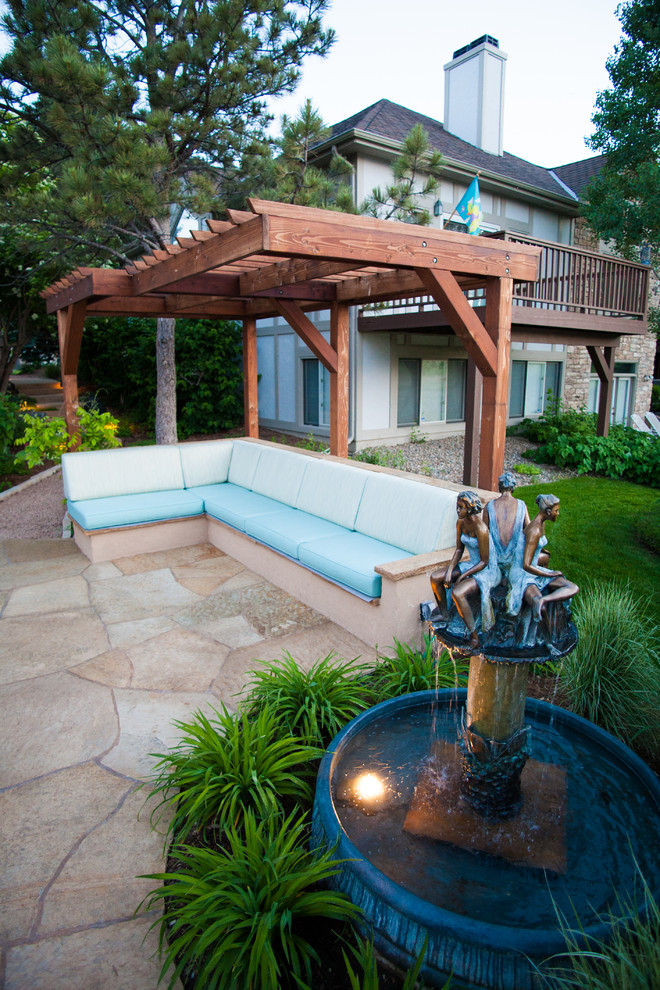 Traditional backyard patio in Denver with a water feature, natural stone pavers and a pergola.