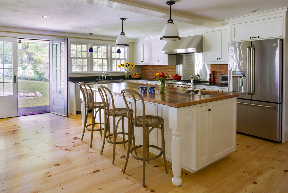 Open concept kitchen - large cottage l-shaped light wood floor open concept kitchen idea in Boston with a farmhouse sink, recessed-panel cabinets, white cabinets, granite countertops, brown backsplash, stainless steel appliances and an island