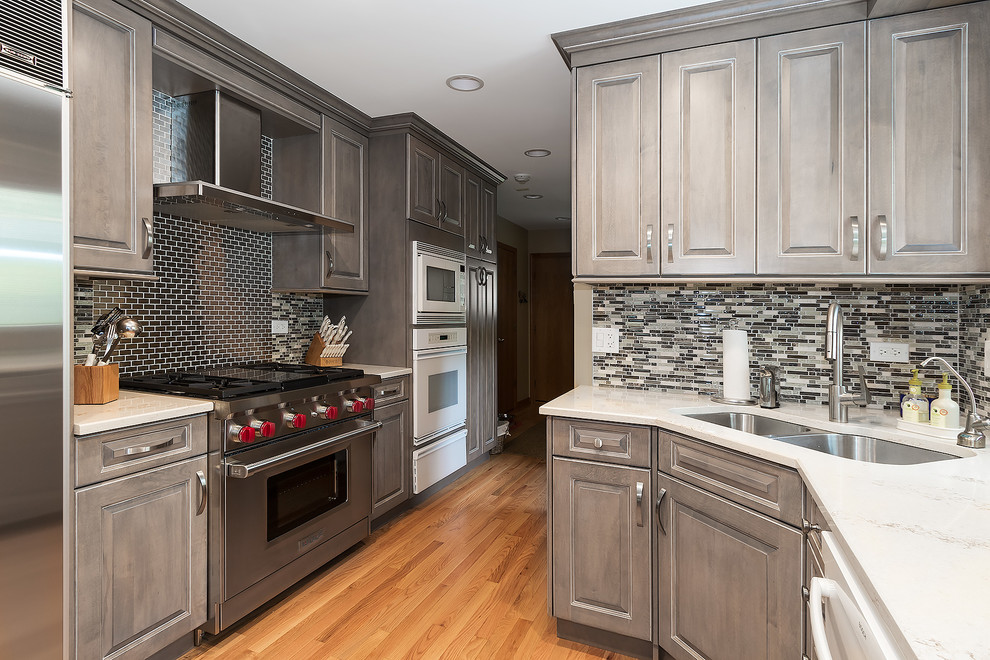 Large transitional galley medium tone wood floor eat-in kitchen photo in Chicago with a double-bowl sink, beaded inset cabinets, gray cabinets, multicolored backsplash and white appliances
