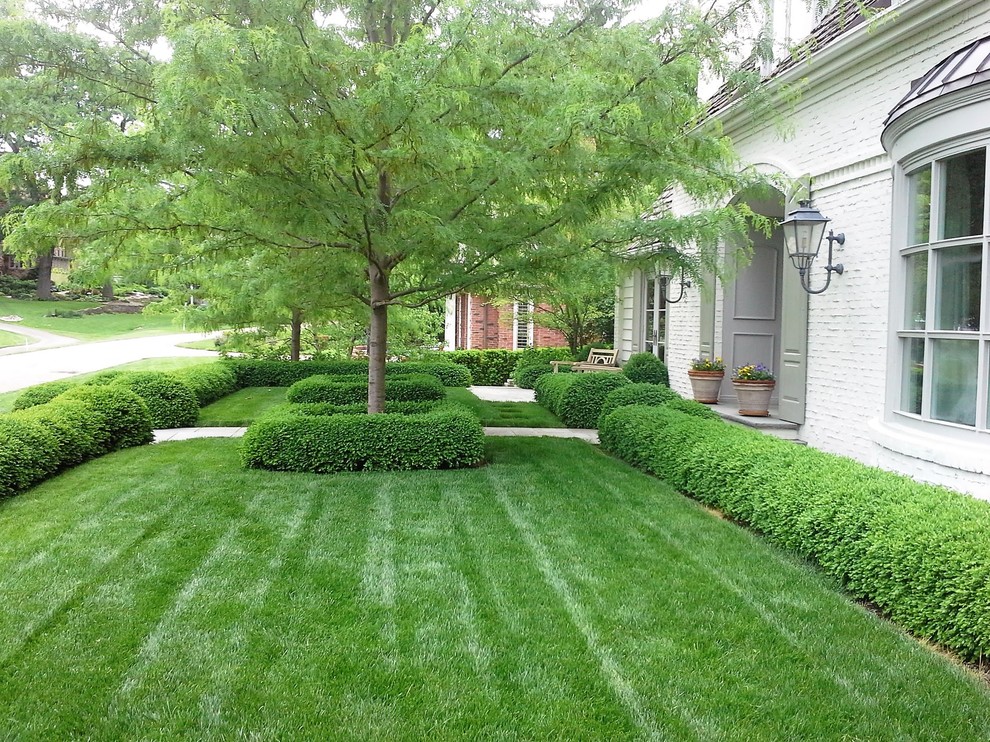 Mid-sized traditional front yard partial sun driveway in Chicago with a retaining wall and natural stone pavers.