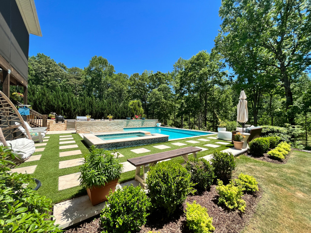 Large traditional backyard custom-shaped pool in Other with with privacy feature and natural stone pavers.