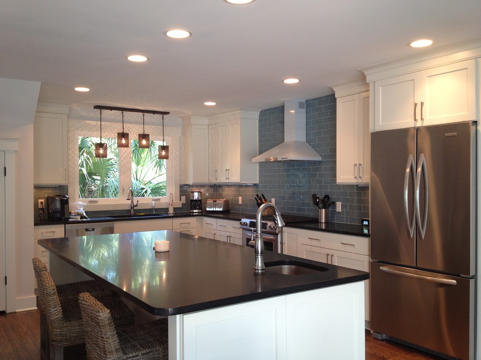 This is an example of a large beach style l-shaped eat-in kitchen in Atlanta with an undermount sink, shaker cabinets, white cabinets, granite benchtops, blue splashback, glass tile splashback, stainless steel appliances, medium hardwood floors and with island.