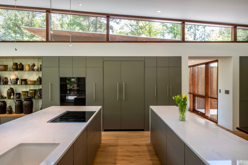 Inspiration for a mid-sized modern u-shaped light wood floor open concept kitchen remodel in Atlanta with a drop-in sink, flat-panel cabinets, gray cabinets, quartzite countertops, paneled appliances, two islands and white countertops