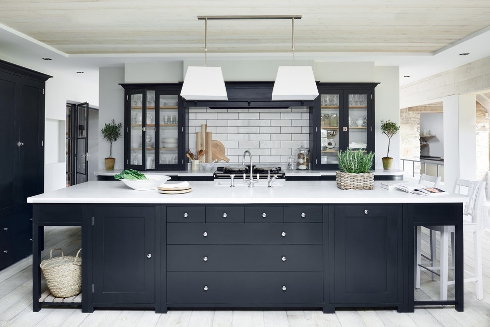 This is an example of a large traditional galley open plan kitchen in Dusseldorf with glass-front cabinets, white splashback, subway tile splashback, painted wood floors and with island.