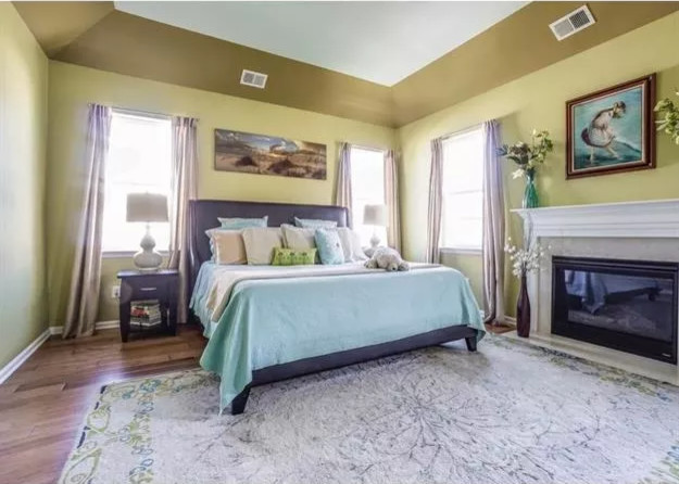 Example of a large transitional master medium tone wood floor and brown floor bedroom design with beige walls, a standard fireplace and a wood fireplace surround