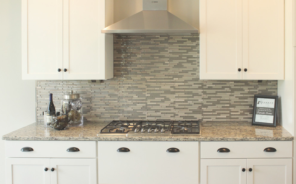 Mid-sized transitional l-shaped medium tone wood floor eat-in kitchen photo in Cedar Rapids with an undermount sink, shaker cabinets, white cabinets, granite countertops, gray backsplash, stainless steel appliances, an island and matchstick tile backsplash