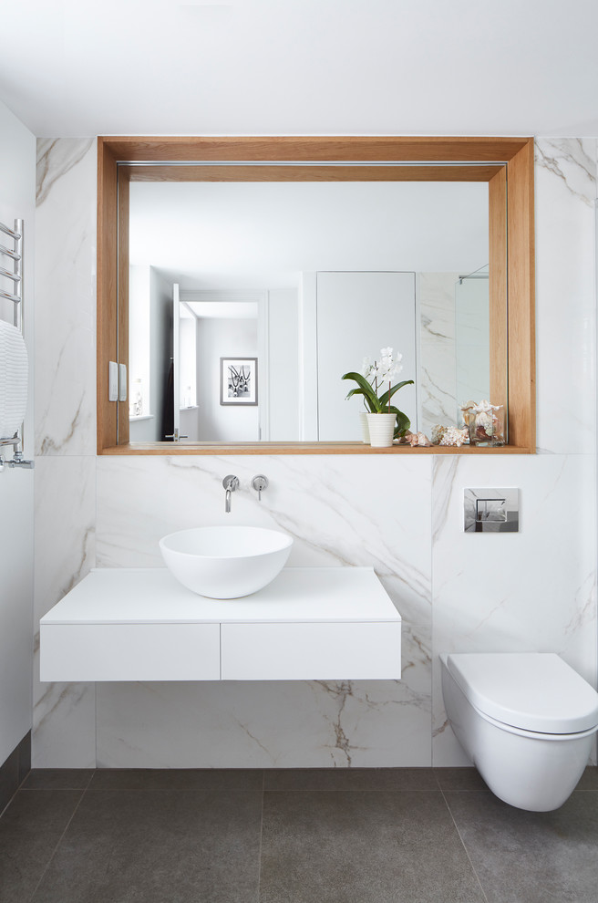 Photo of a mid-sized contemporary kids bathroom in London with white cabinets, an open shower, a wall-mount toilet, white tile, marble, white walls, a vessel sink, grey floor, an open shower and white benchtops.