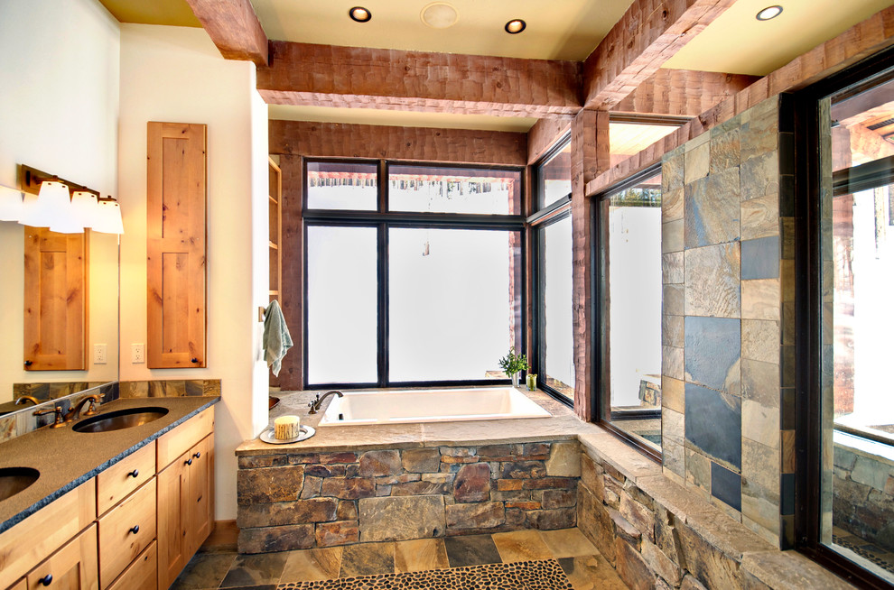 This is an example of a mid-sized country bathroom in Other with an undermount sink, flat-panel cabinets, light wood cabinets, zinc benchtops, a drop-in tub, gray tile, ceramic tile, white walls and ceramic floors.