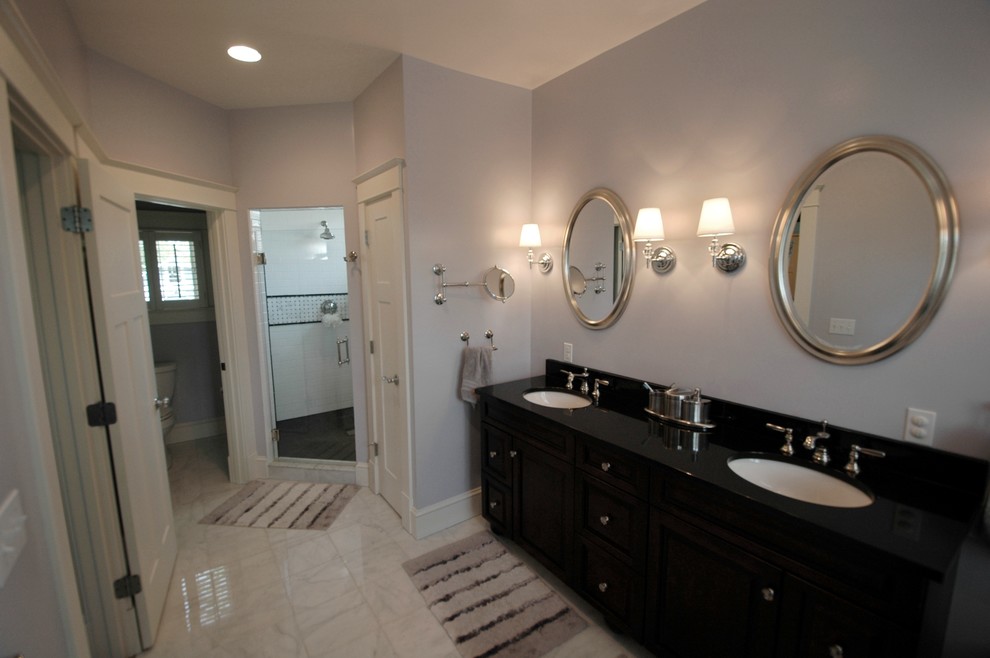 Large transitional master bathroom in DC Metro with an undermount sink, raised-panel cabinets, dark wood cabinets, granite benchtops, a corner shower, a two-piece toilet, gray tile, stone tile, purple walls and marble floors.