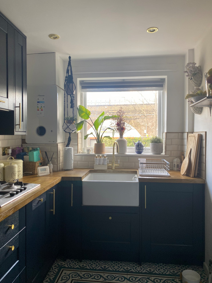 Mid-sized contemporary u-shaped separate kitchen in London with a farmhouse sink, blue cabinets, wood benchtops, white splashback, ceramic splashback, porcelain floors, no island, blue floor and coffered.