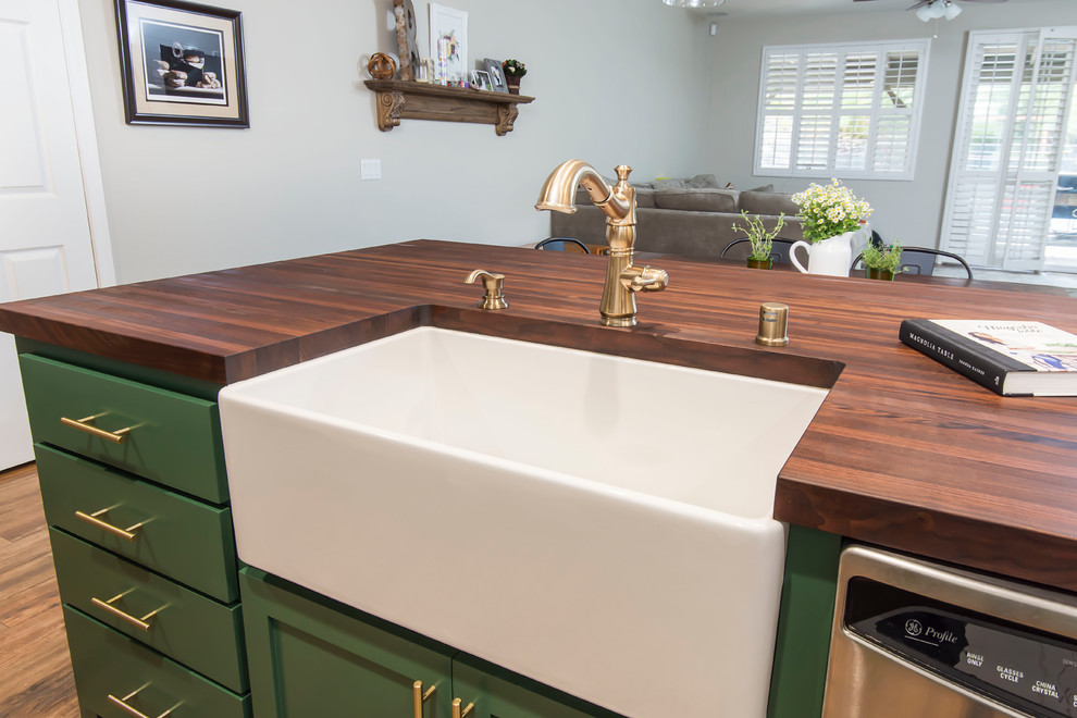 Large transitional l-shaped eat-in kitchen in Los Angeles with a farmhouse sink, shaker cabinets, green cabinets, quartz benchtops, multi-coloured splashback, porcelain splashback, stainless steel appliances, with island, brown floor and white benchtop.