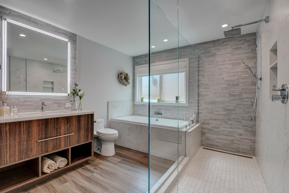 Inspiration for a large contemporary master bathroom in San Francisco with flat-panel cabinets, medium wood cabinets, a drop-in tub, an open shower, a one-piece toilet, gray tile, ceramic tile, grey walls, ceramic floors, a drop-in sink, engineered quartz benchtops, brown floor, an open shower and grey benchtops.