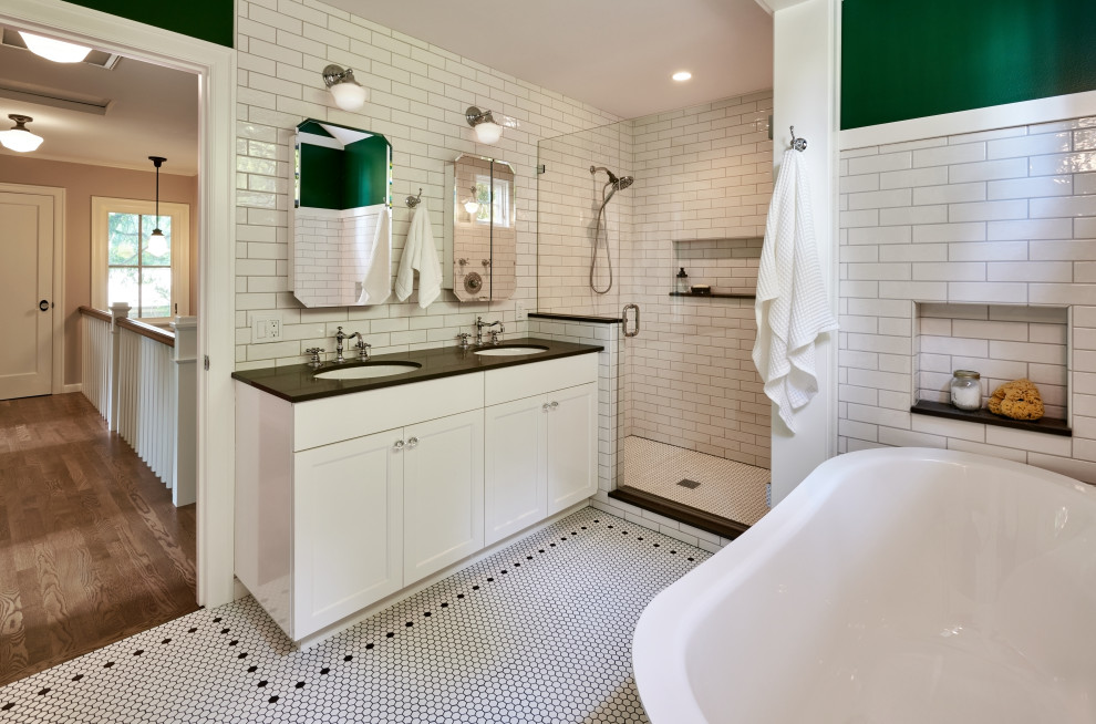Foto på ett stort amerikanskt grå badrum, med ett badkar med tassar, en dubbeldusch, vit kakel, tunnelbanekakel, dusch med gångjärnsdörr, vita skåp och vitt golv