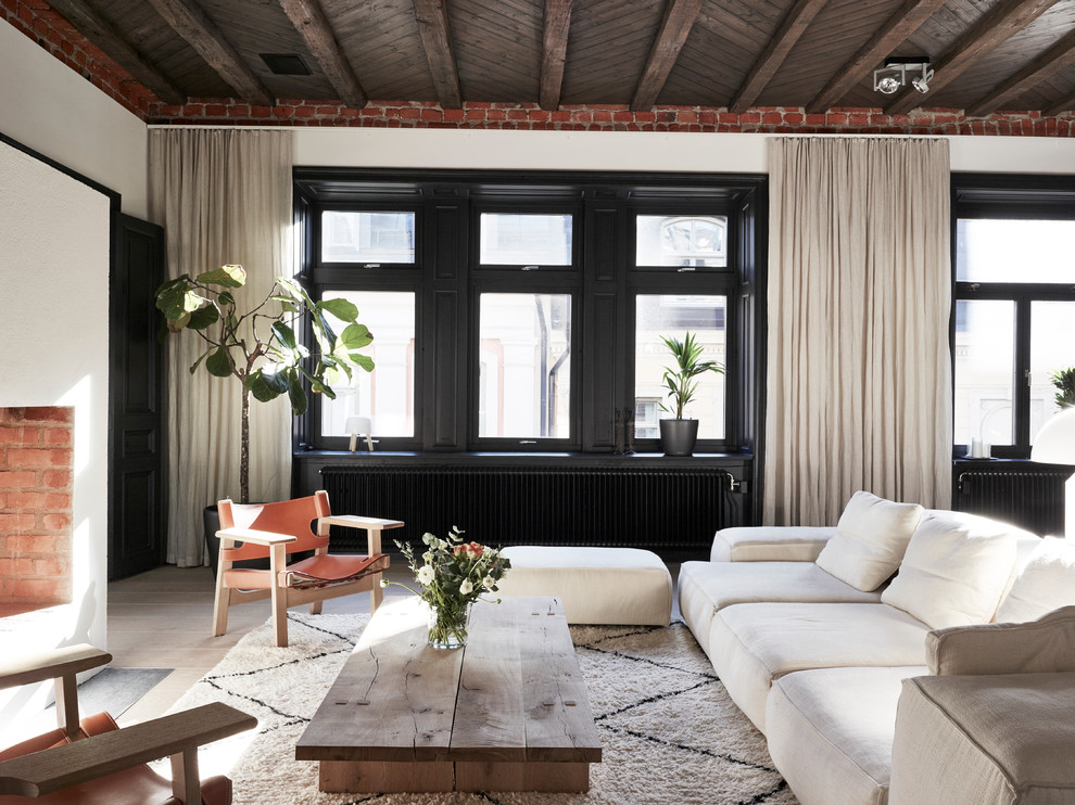 This is an example of a mid-sized scandinavian formal open concept living room in Stockholm with white walls, a standard fireplace, no tv and light hardwood floors.