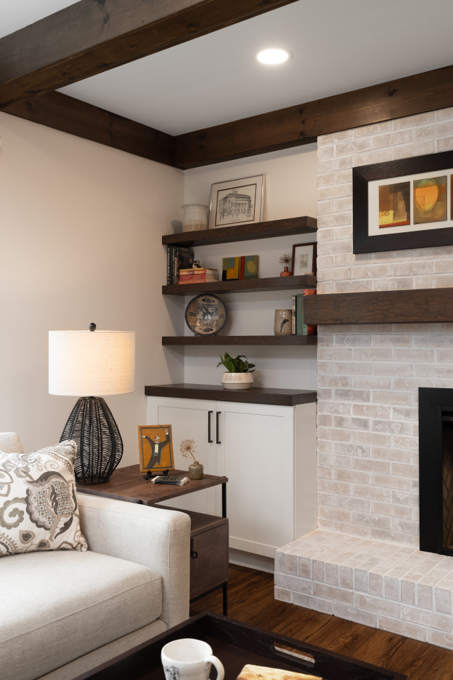 デトロイトにある中くらいなトランジショナルスタイルのおしゃれなオープンリビング (白い壁、標準型暖炉、レンガの暖炉まわり、茶色い床、表し梁、壁掛け型テレビ) の写真