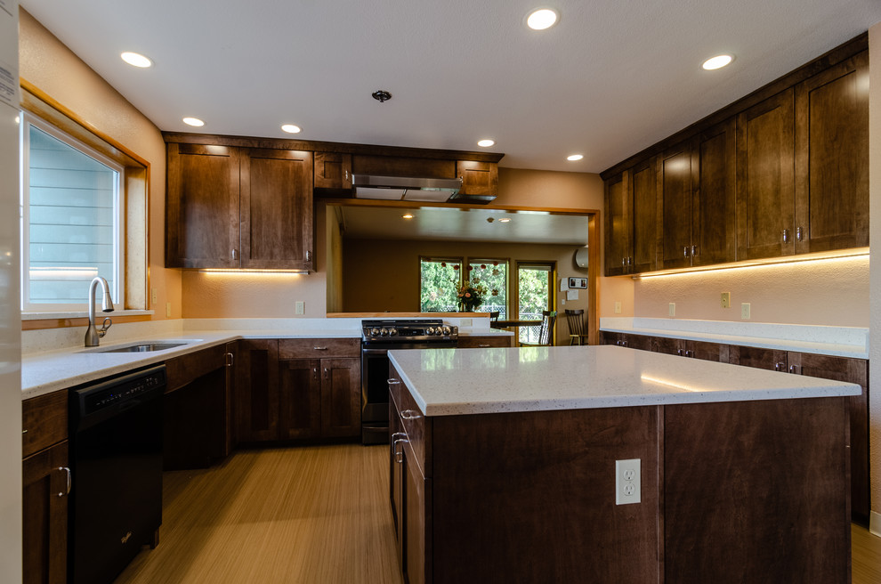 Large transitional u-shaped light wood floor and beige floor enclosed kitchen photo with an undermount sink, recessed-panel cabinets, dark wood cabinets, quartz countertops, stainless steel appliances, an island and white countertops