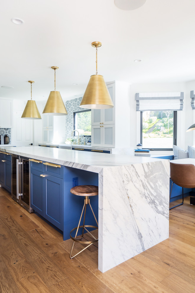 This is an example of a large contemporary eat-in kitchen in Orange County with an undermount sink, shaker cabinets, blue cabinets, marble benchtops, multi-coloured splashback, marble splashback, panelled appliances, medium hardwood floors, with island, brown floor and white benchtop.