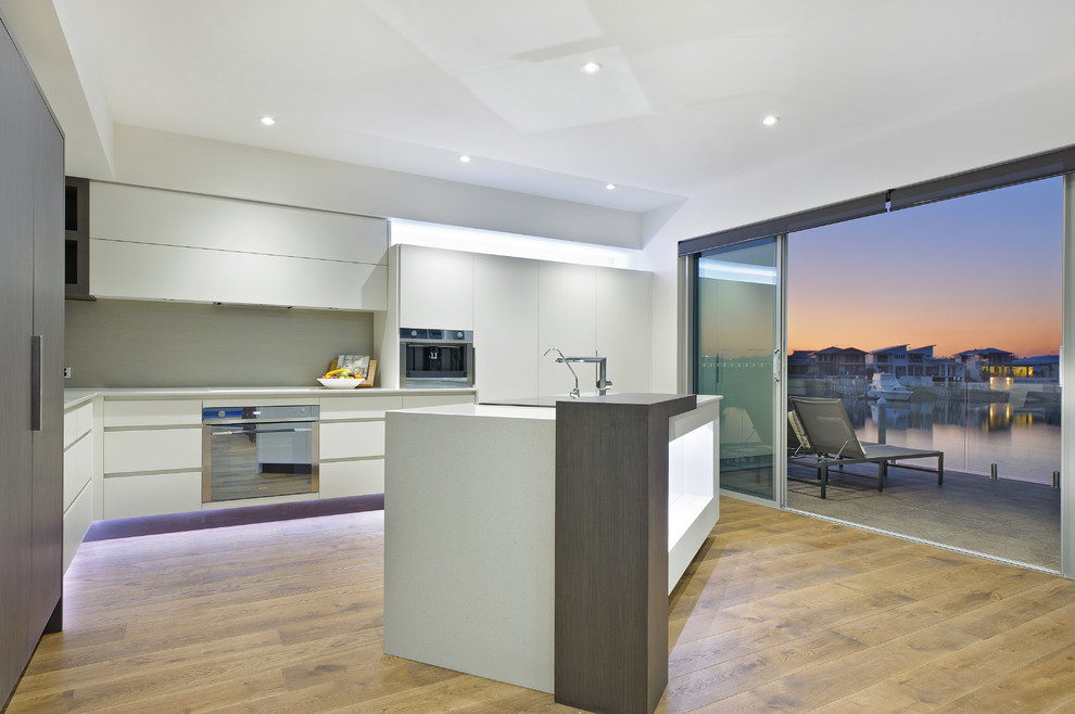 Design ideas for a contemporary l-shaped kitchen in Sydney with flat-panel cabinets, white cabinets and stainless steel appliances.