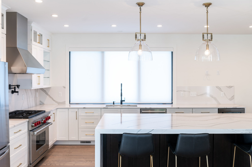 Bild på ett vintage vit vitt kök och matrum, med skåp i shakerstil, vita skåp, marmorbänkskiva, vitt stänkskydd, stänkskydd i marmor, rostfria vitvaror, en köksö och brunt golv