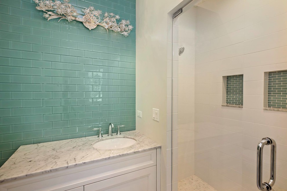 Photo of a mid-sized beach style master bathroom in Chicago with recessed-panel cabinets, white cabinets, a corner shower, a one-piece toilet, white walls, an undermount sink, blue tile, white tile, subway tile and marble benchtops.