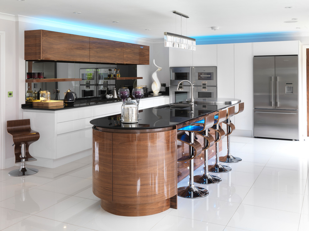 Large contemporary l-shaped open plan kitchen in Buckinghamshire with a double-bowl sink, flat-panel cabinets, dark wood cabinets, granite benchtops, metallic splashback, mirror splashback, stainless steel appliances and with island.
