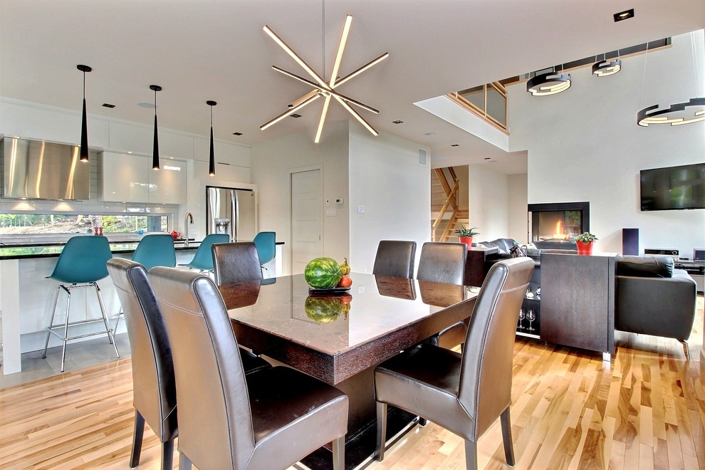 Photo of a mid-sized modern kitchen/dining combo in Montreal with white walls, light hardwood floors and a two-sided fireplace.