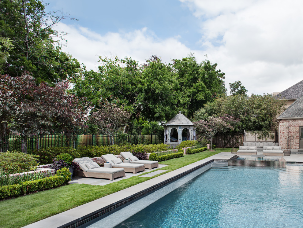 This is an example of a mid-sized transitional backyard rectangular lap pool in Houston with a hot tub and natural stone pavers.