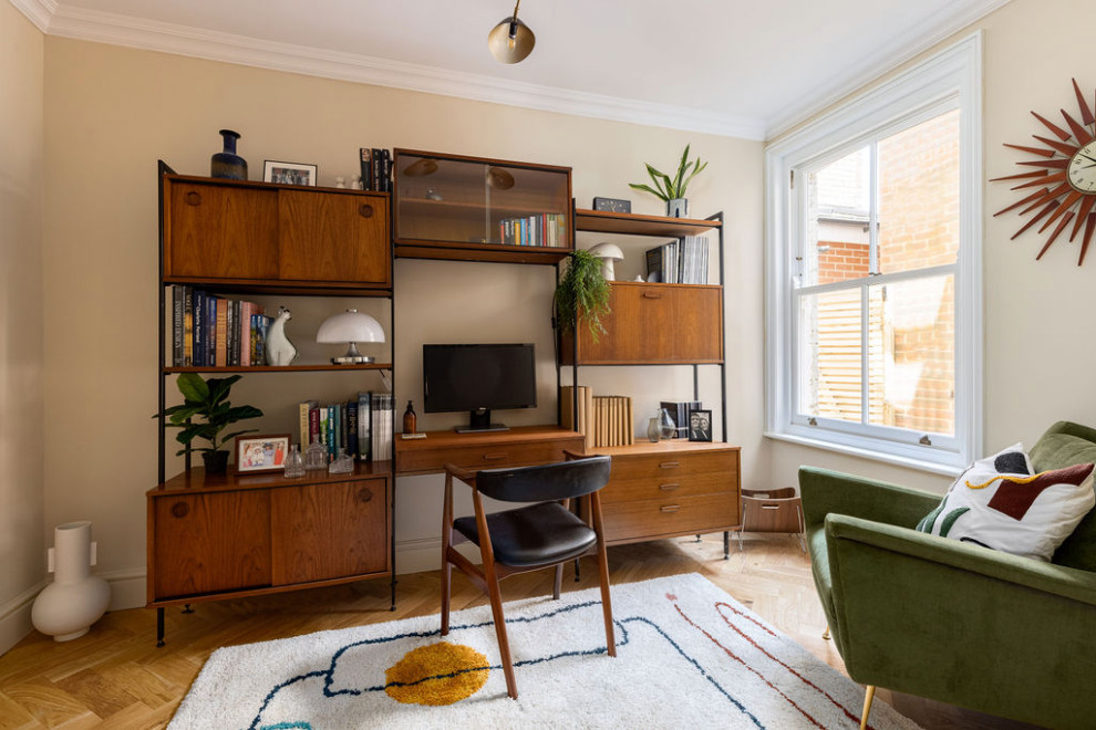 Mittelgroßes Retro Arbeitszimmer ohne Kamin mit Arbeitsplatz, beiger Wandfarbe, braunem Holzboden, freistehendem Schreibtisch und beigem Boden in Hampshire