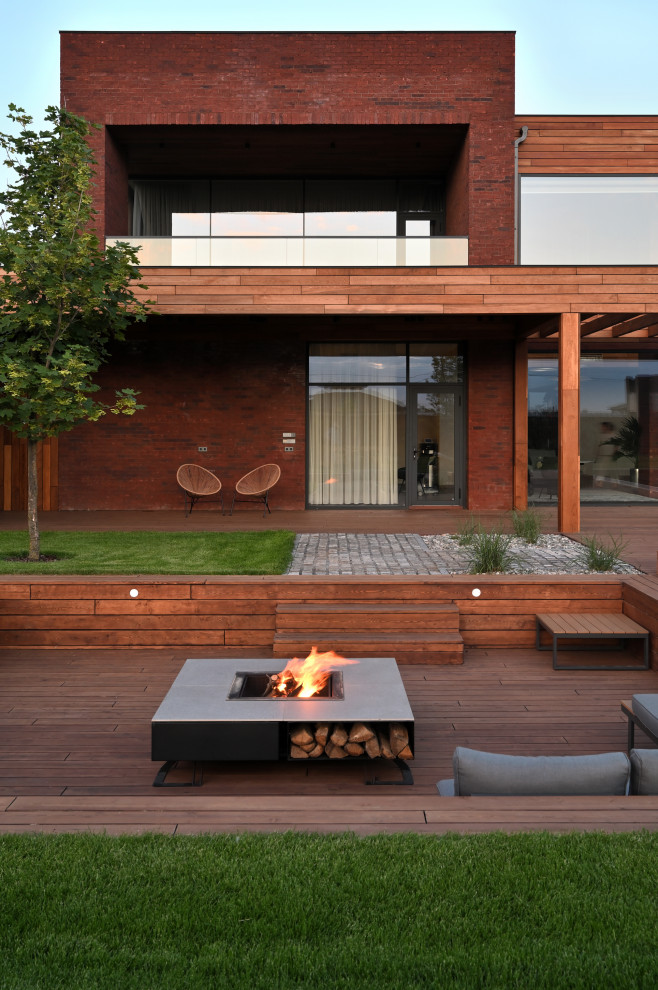 This is an example of a large contemporary courtyard patio in Moscow with with fireplace and an awning.
