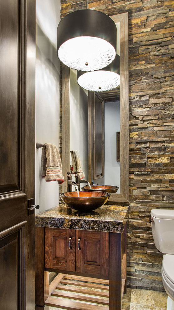 This is an example of a mid-sized traditional bathroom in Salt Lake City with medium wood cabinets, a two-piece toilet, beige tile, stone tile, black walls, travertine floors, a vessel sink and granite benchtops.